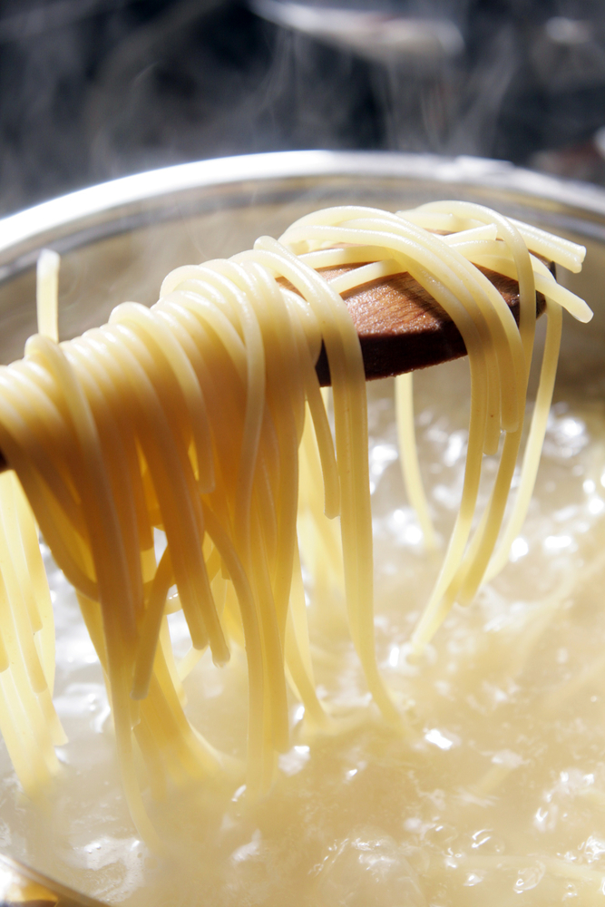 lifting spaghetti out of a pan of boiling water