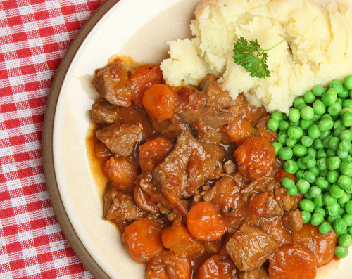 beef casserole with peas and mashed potato on a plate