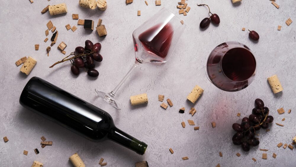 bottle of red wine laid on the floor with oak chips and grapes scattered around