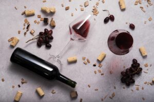 bottle of red wine laid on the floor with oak chips and grapes scattered around